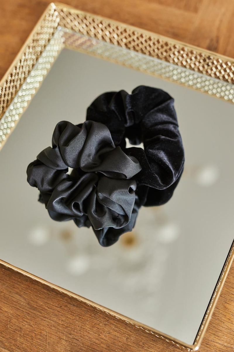 Czarna gumka do włosów Franka K typu scrunchie, wykonana z delikatnej, błyszczącej satyny.